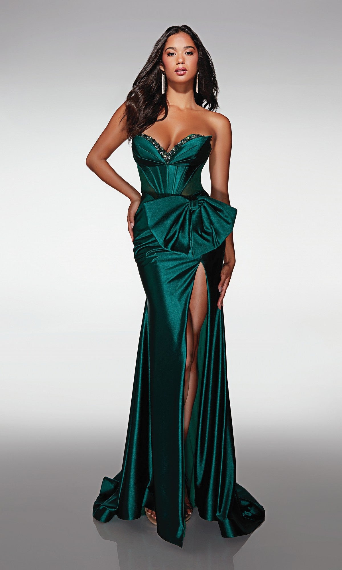Woman in the Alyce 62156 long formal dress in pine, featuring a strapless beaded sweetheart neckline, large waist bow, and a high left leg slit.
